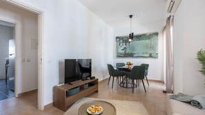 A modern living room with a flat-screen TV, dining table with chairs, and a large abstract painting on the wall. - Casa Horizonte - Old Town Lagos (Lagos)