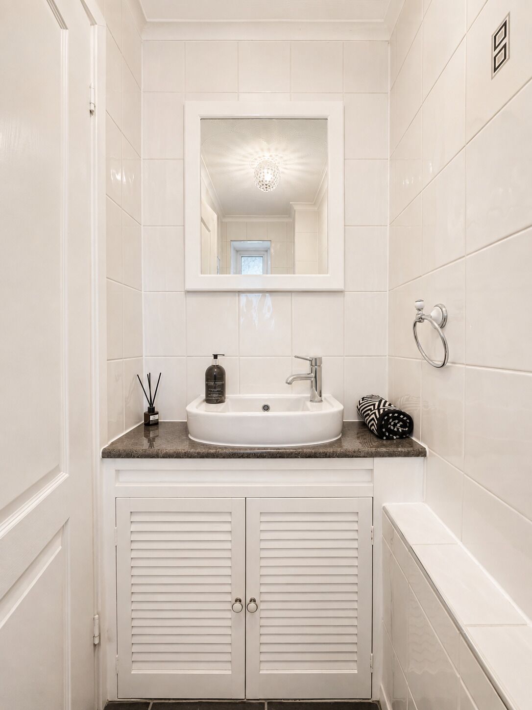 A bathroom with a white sink, a mirror above it, and a towel rack.