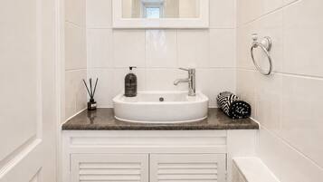 A bathroom with a white sink, a mirror above it, and a towel rack.