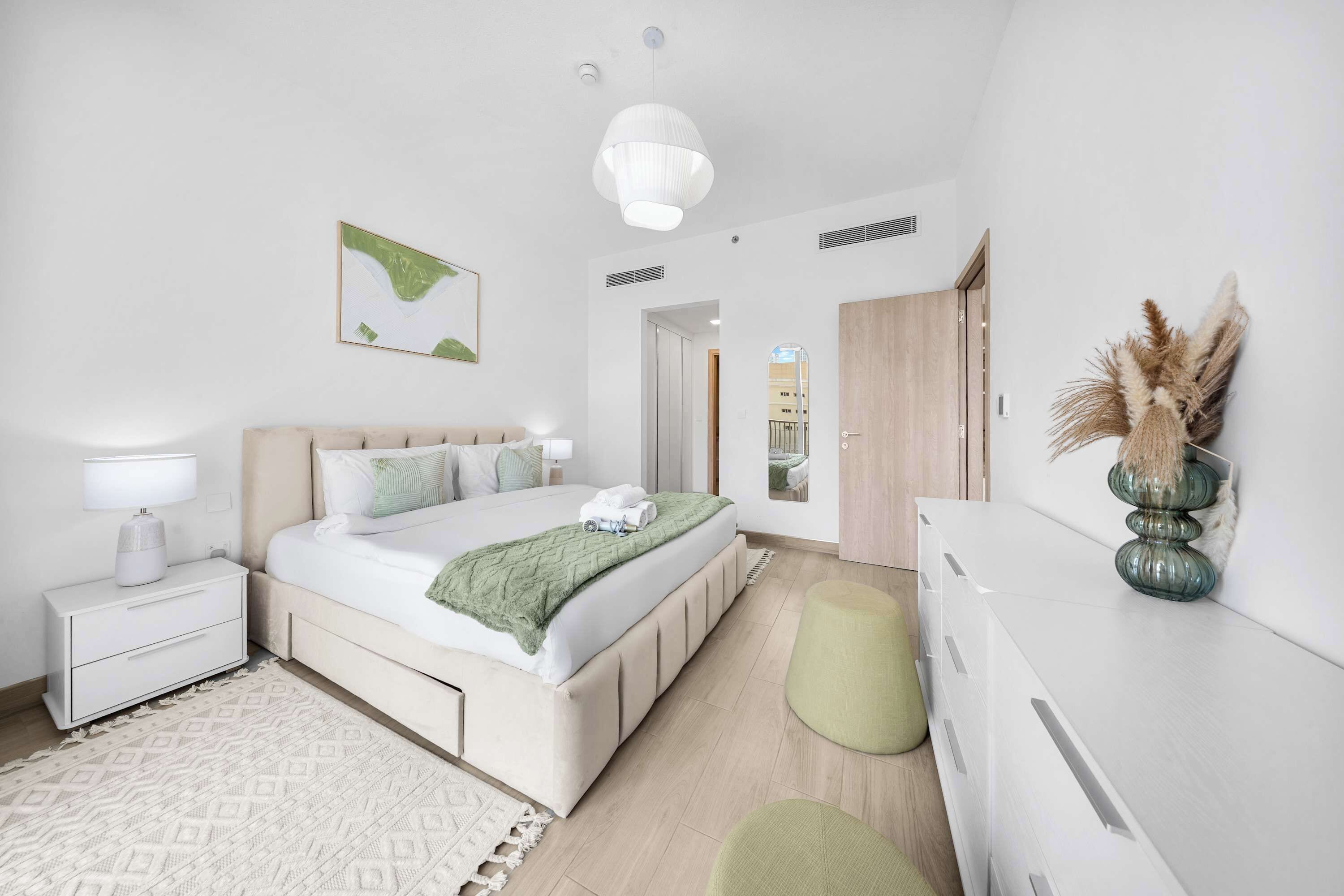 Ein modernes Schlafzimmer mit Bett, Nachttisch, Lampe und Spiegel.