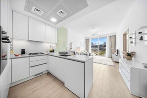 Een moderne keuken met een centraal eiland, ingebouwde apparatuur en uitzicht naar buiten.