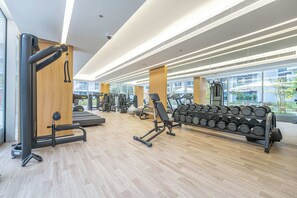 A modern gym with various exercise equipment, large windows, and a wooden floor. - StayShort - Stylish 1 Bedroom in JVC - Sleeps 4 (JVC)