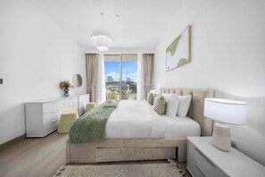 A modern bedroom with a large bed, a bedside table, a lamp, a dresser, and a view of the city through the window. - StayShort - Stylish 1 Bedroom in JVC - Sleeps 4 (JVC)