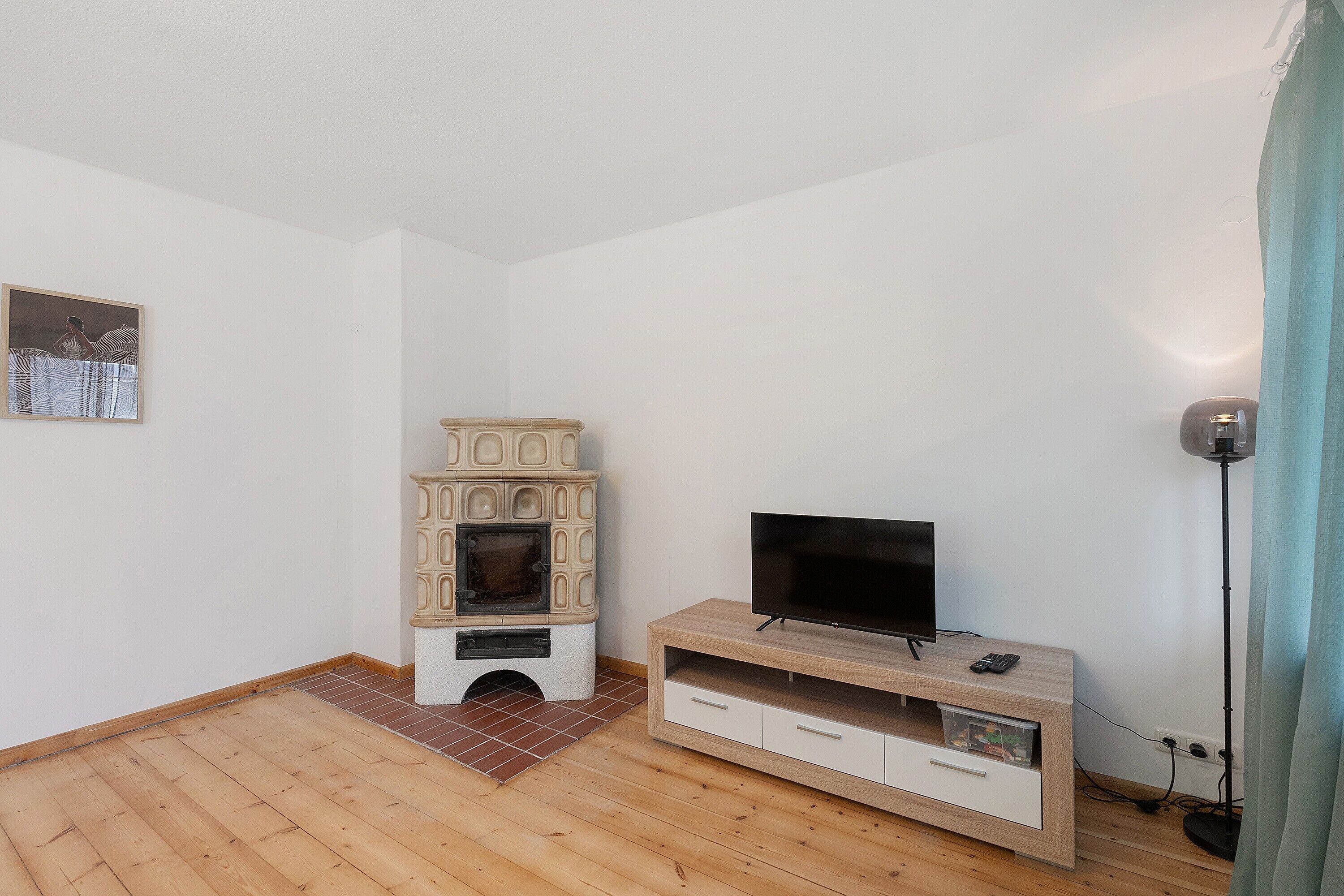 A room with a television on a wooden stand, a small fireplace, and a picture on the wall.