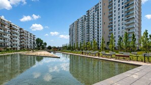 A modern residential area with a clear water feature, high-rise apartment buildings, and a well-maintained lawn. - Letnica 159 | Sea View | 2 Bedrooms (Gdańsk)