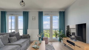 A modern living room with a sofa, coffee table, and a TV on a wooden cabinet. - Letnica 159 | Sea View | 2 Bedrooms (Gdańsk)