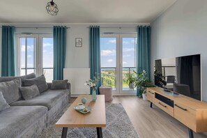 Ein modernes Wohnzimmer mit einer Couch, einem Couchtisch und einem Fernseher auf einer Holzkommode.