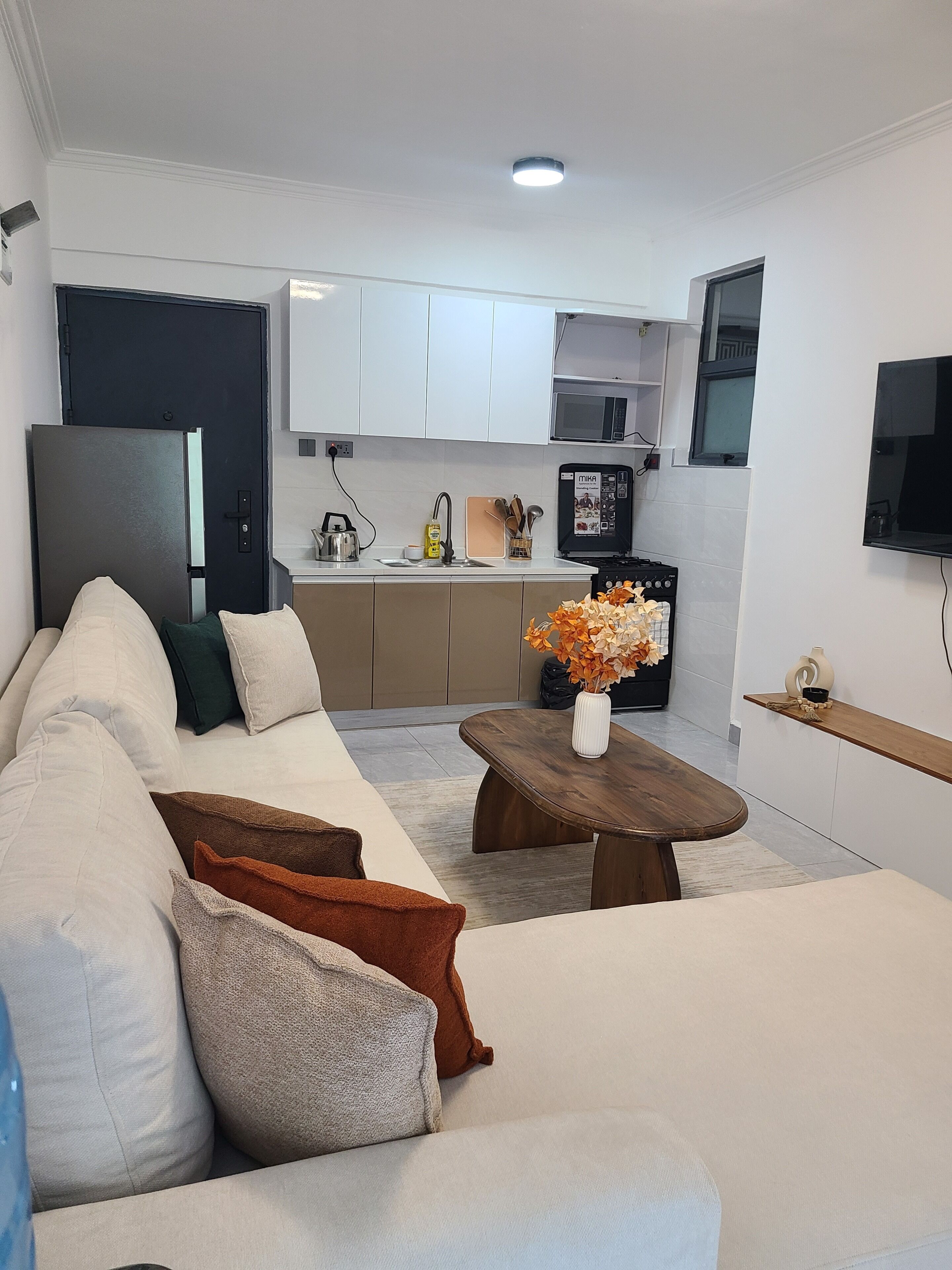 Ein modernes Wohnzimmer mit Sofa, Couchtisch und einer Küchenzeile im Hintergrund.