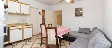 Un espacio habitable compacto con kitchenette, comedor y sofá.