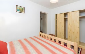 A bedroom with a bed, a wooden wardrobe, a mirror, and a framed picture on the wall. - One-Bedroom Apartment with Mountain View, Wi-Fi, and Air Conditioning (Tkon)