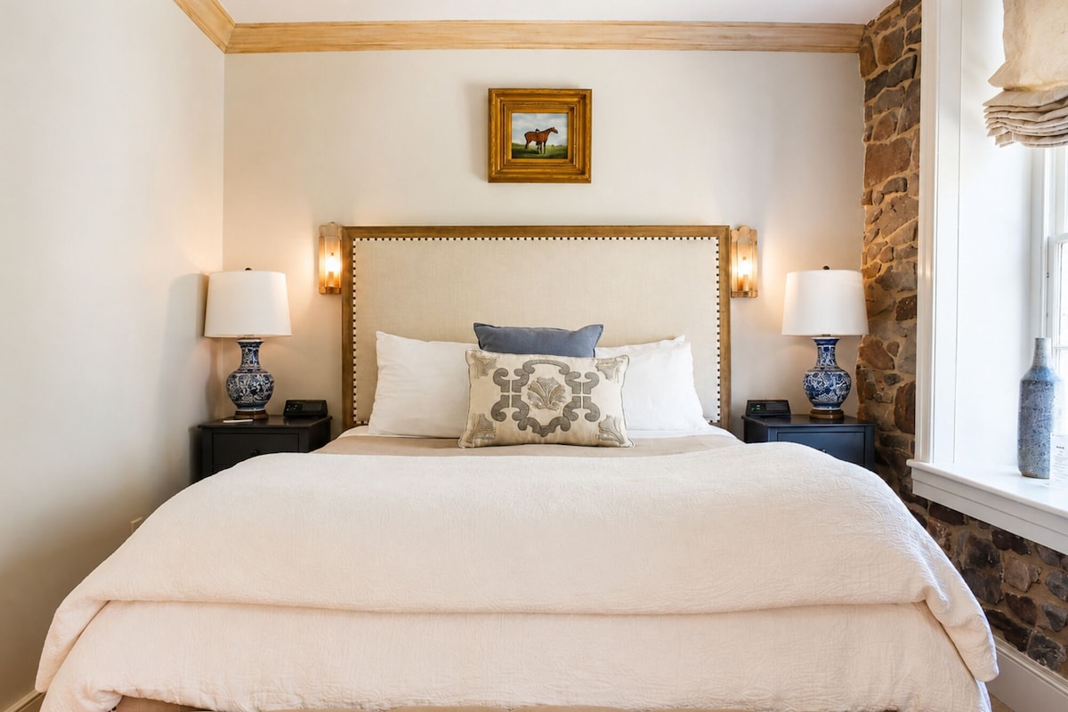 A bed with a wooden headboard, two bedside lamps, and a framed picture on the wall.