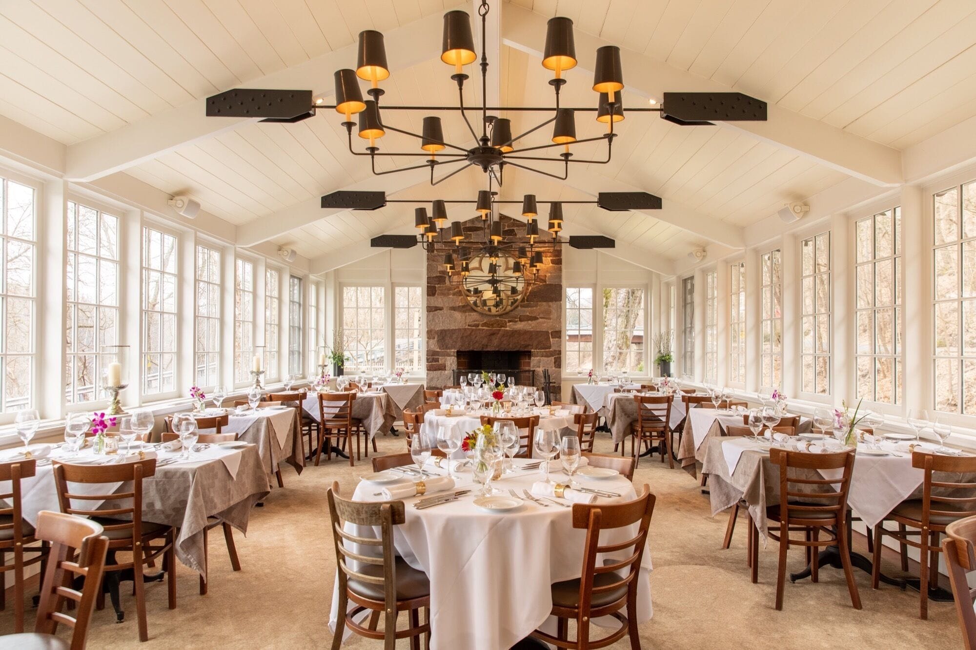Un restaurante con varias mesas, una chimenea de piedra y un candelabro.