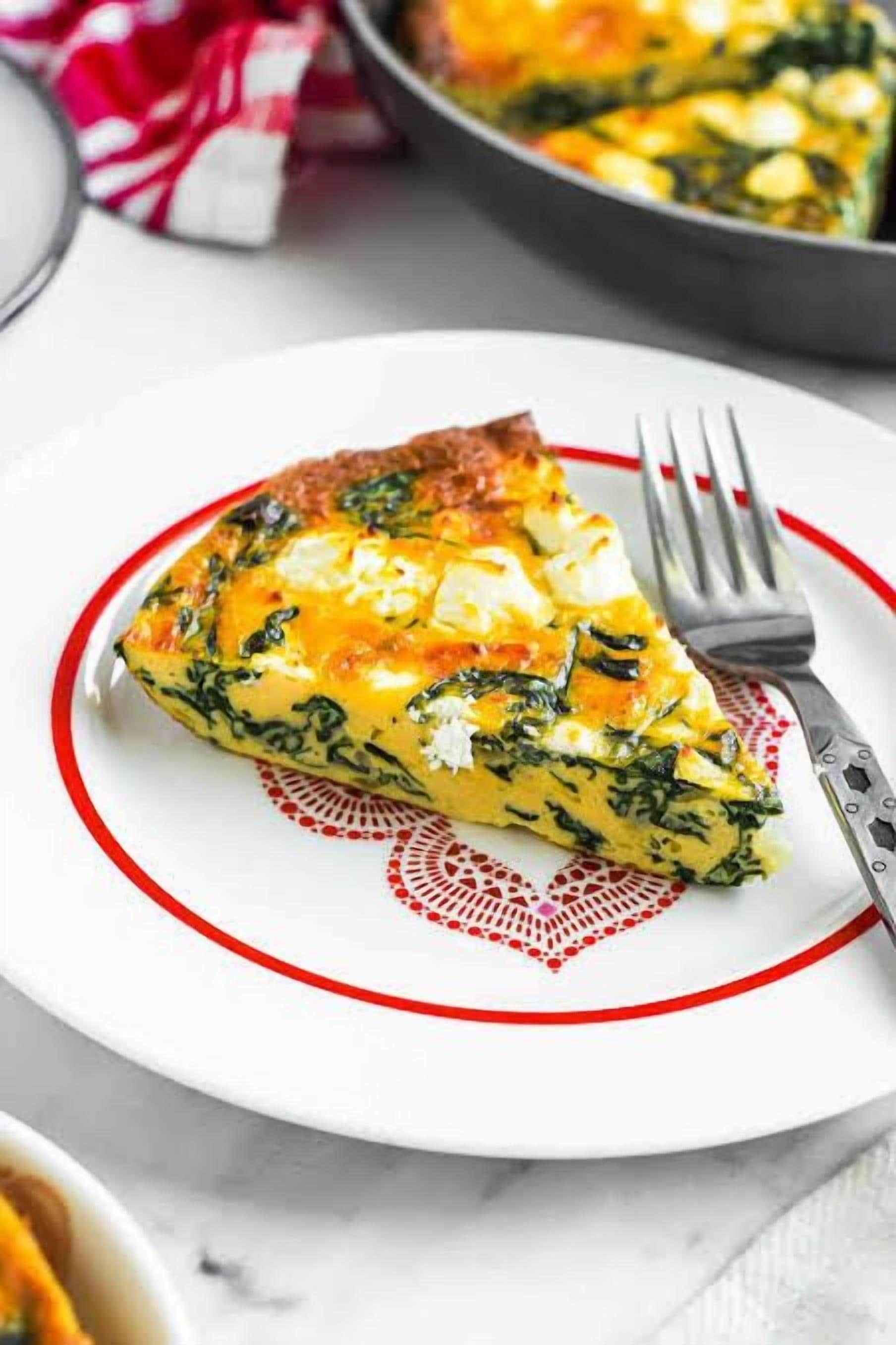 Una porción de quiche sobre un plato blanco con borde rojo.