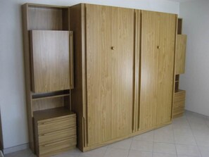 Ein großer, hölzerner Kleiderschrank mit mehreren Fächern und Schubladen.