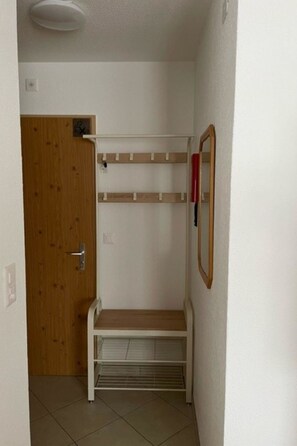 A narrow hallway with a wooden door, a white bench, and a mirror on the wall. - Bergtreu 13 # 2-bed apartment, Dusche, WC 2-Bettwohnung, Dusche, WC by Interhome (Leukerbad)