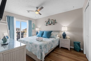 A bedroom with a bed, nightstands, a ceiling fan, a window with curtains, and a view of the outside. - Infinity Dream𓇼Ocean Views+Sleeps 14+Golf Cart (Oak Island)