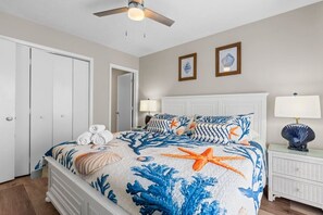 Ein Schlafzimmer mit einem Bett, zwei Wandlampen, einem Deckenventilator, einer weißen Kommode und einer Tür.