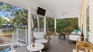 A covered outdoor area with seating, a television, and a ceiling fan. - Birdsong Cottage𓇼Island Retreat+Central Location (Oak Island)