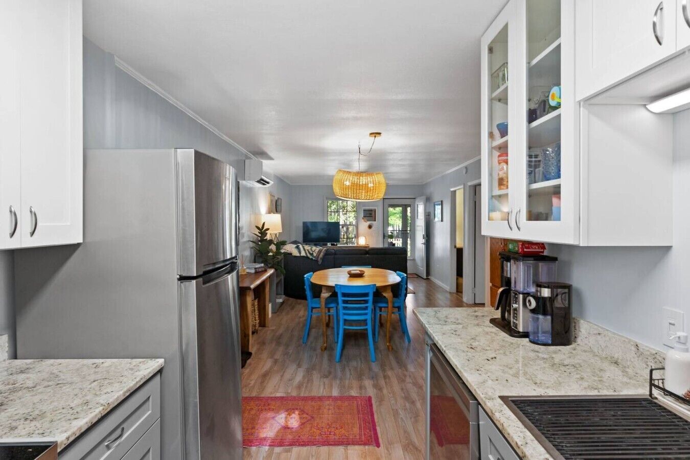 A modern kitchen with a central island, stainless steel appliances, and a dining area with blue chairs.