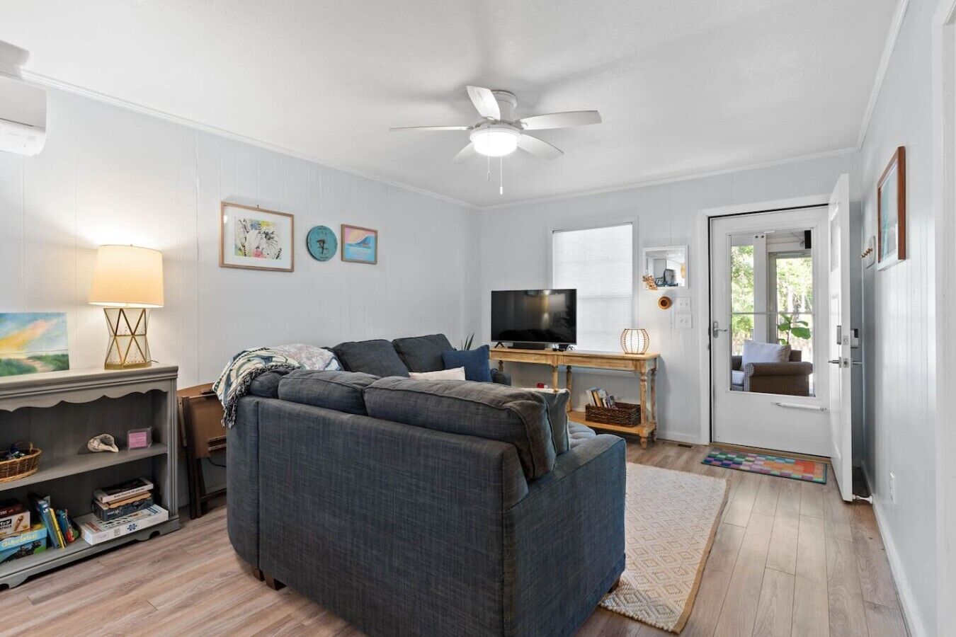 A living room with a sofa, TV, lamp, and artwork on the wall.