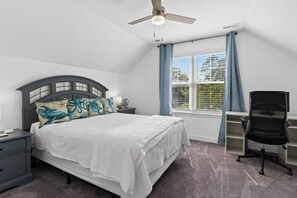 A bedroom with a bed, a desk, a chair, a ceiling fan, and a window with curtains. - My Three Buoys𓇼Sleeps 10+Game Room+Spacious (Oak Island)