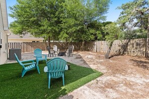 A backyard with a lawn, a wooden fence, and outdoor furniture. - My Three Buoys𓇼Sleeps 10+Game Room+Spacious (Oak Island)