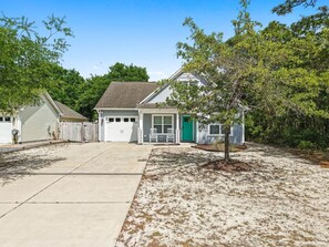 A residential property with a front yard, a garage, and a small porch area. - My Three Buoys𓇼Sleeps 10+Game Room+Spacious (Oak Island)
