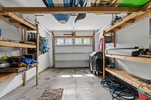En garage med træhylder, en overdækket arbejdsbord og en garageport.