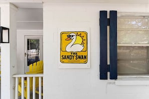Un edificio con un letrero que dice 'The Sandy Swan' y una silla amarilla en el exterior.