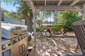A covered outdoor area with a grill, chairs, and a bicycle. - Sandy Swan𓇼Cozy Cottage Vibes+Golf Cart+Hot Tub (Oak Island)