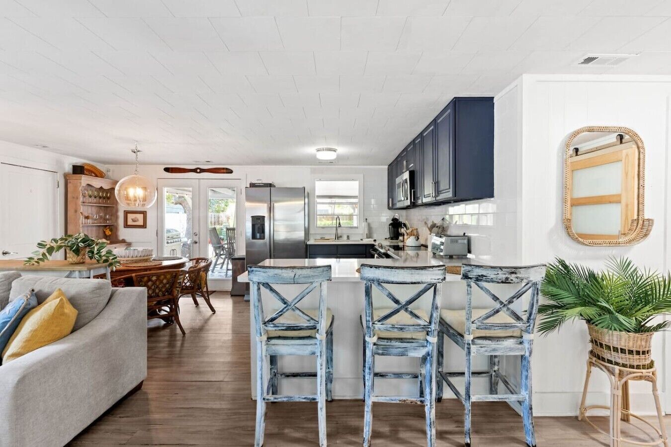 A modern kitchen with a central island, bar stools, and a dining area with a sofa and chairs.