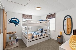 A bunk bed room with a bookshelf, a mirror, and a window with curtains. - Sandy Swan𓇼Cozy Cottage Vibes+Golf Cart+Hot Tub (Oak Island)