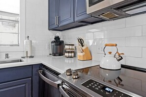 A modern kitchen with a dishwasher, a coffee maker, a kettle, and a knife block. - Sandy Swan𓇼Cozy Cottage Vibes+Golf Cart+Hot Tub (Oak Island)