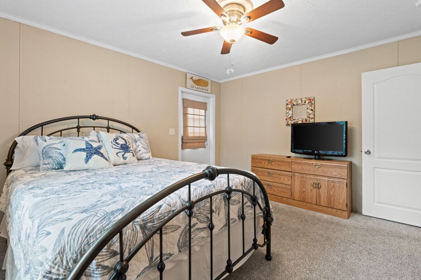 Une chambre à coucher avec un lit, un ventilateur de plafond, une commode et un téléviseur.