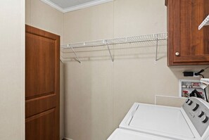 A laundry room with a white washing machine, a wooden door, and a metal drying rack.