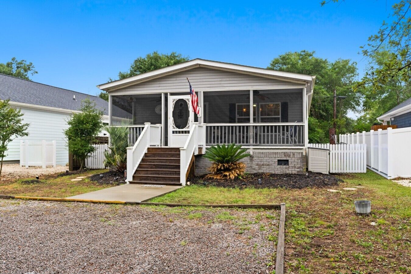 A single-story house with a front porch, a small staircase, and a flag.