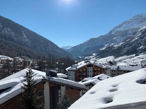 Ein verschneites Bergdorf mit Gebäuden und blauem Himmel.