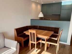 A modern kitchen with built-in cabinets and a dining area with a wooden table and chairs.