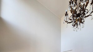 Ein Korridor mit Holzdielenparkett, einem Glastischchen mit einer Vase und drei gerahmten Bildern an der Wand.