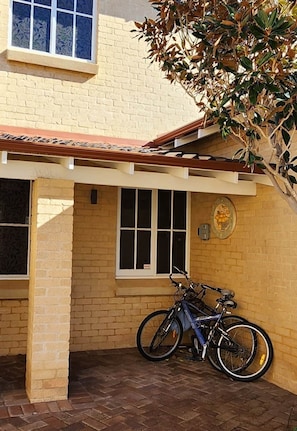 A building with a brick facade, a tiled roof, and a bicycle parked outside. - Mandurah Holiday Apartments ‘Pelican’ (Dudley Park)