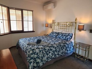 A bedroom with a bed, bedside lamps, and a window with blinds. - Mandurah Holiday Apartments ‘Pelican’ (Dudley Park)