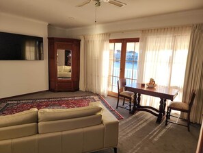 Un salon comprenant un canapé, une table à manger avec des chaises, une grande fenêtre avec des rideaux et un ventilateur de plafond.