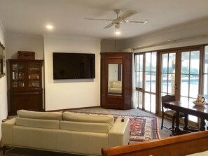 Una sala de estar con un sofá, un televisor, un mueble y una mesa de comedor con sillas.
