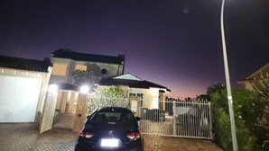 Ein Wohnhaus bei Nacht mit einem Auto auf der Auffahrt, einem verschlossenen Eingang und einer Straßenlaterne.
