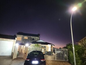 Ein Wohnhaus bei Nacht mit einem Auto auf der Auffahrt, einem verschlossenen Eingang und einer Straßenlaterne.