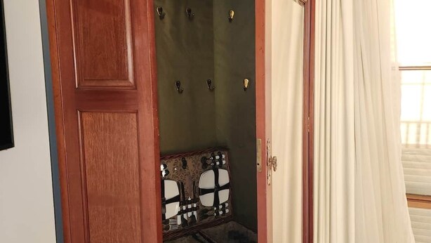 Ein Holzkleiderschrank mit Spiegel, eine kleine Kommode und eine Tür.