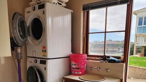 Ein Waschraum mit zwei Waschmaschinen, einem Waschbecken und einem Fenster mit Blick ins Freie.