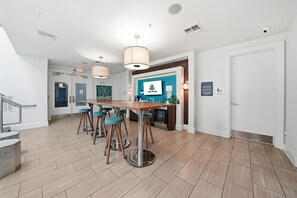 Une cuisine moderne avec un coin bar, un plancher en bois et des luminaires suspendus.