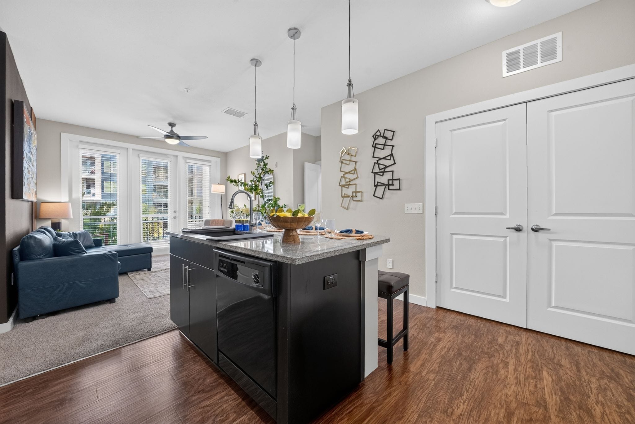 A modern kitchen with a central island, a dining area with a sofa, and a large white door.