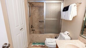 Een badkamer met douche, toilet en een handdoekhouder.
